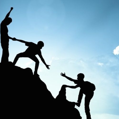 People helping another person climb a mountain to showcase the article Why work with a surrogacy agency